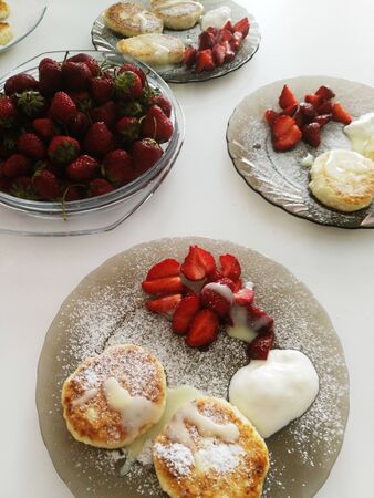 Curd berry dessert on a plate sprinkled with powdered sugar next to fresh strawberries.の写真素材