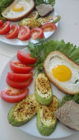 Toasts with fried egg and zucchini grilled with fresh tomatoes on a plate.の写真素材