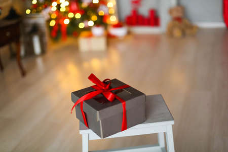 Christmas box with a gift tied with a ribbon on the background of a Christmas treeの写真素材