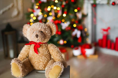 Christmas Teddy on the background of a fireplace with candles and a Christmas treeの写真素材