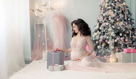 Close up of a woman in a dress sitting near a box with a Christmas giftの写真素材