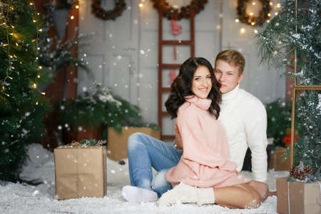 Married couple in love a man and a young woman pregnant on new years eve near the Christmas treeの写真素材