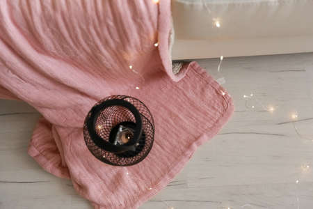 a metal candlestick stands on the floor and beneath it a pink blanketの写真素材