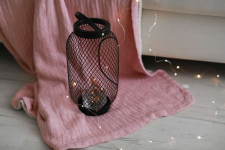 a metal candlestick stands on the floor and beneath it a pink blanketの写真素材