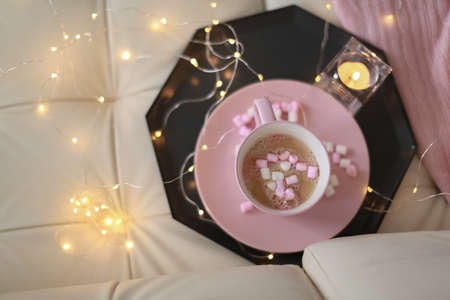 A mug of pink color with air caramels are in a tray on a light sofaの写真素材