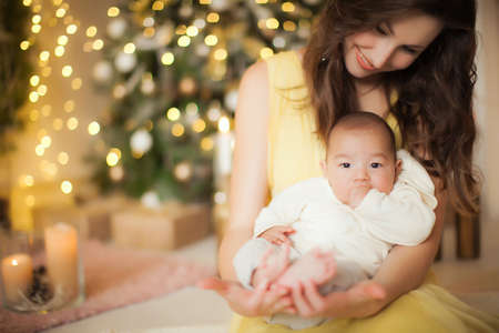 A young mother on new years eve holds a baby in her armsの写真素材