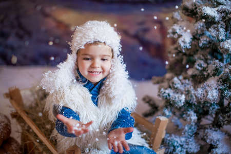Portrait of a boy close-up on the background of a night village during a snowfallの写真素材