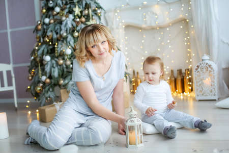 Child and mother in light pajamas on the background of a Christmas treeの写真素材