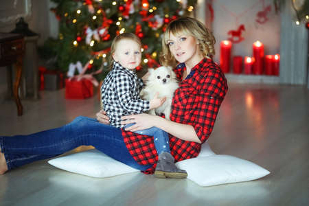 Mother with child in plaid shirts on the background of Christmas red candles and Christmas treeの写真素材