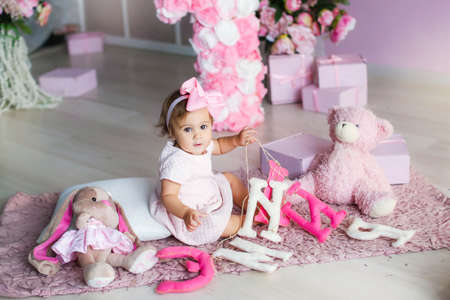Baby with a pink dress on a background of pink adornment with a pink bow on her headの写真素材