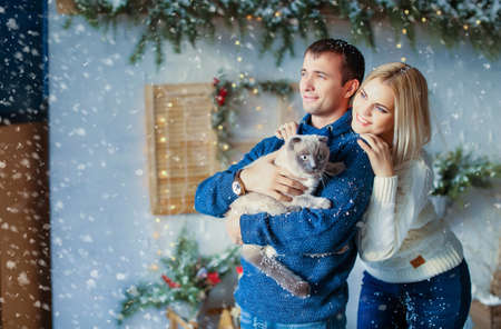 Close up of a couple on Christmas eve with a pet cat in his armsの写真素材