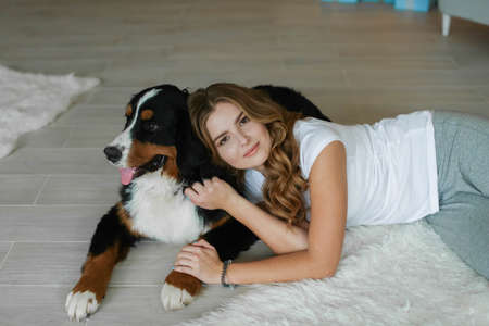 A beautiful woman is lying on the floor next to a domestic purebred pet a large dogの写真素材