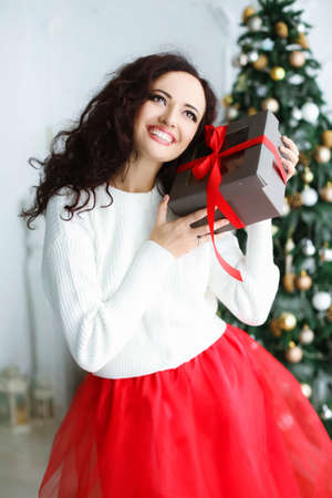 Woman model in a red dress in a photo studio holding a New Years gift in her handsの写真素材