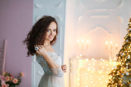 Leggy brunette in an elegant dress decorates a Christmas treeの写真素材