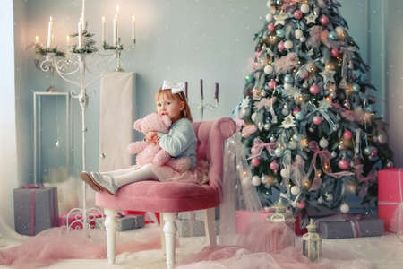 Christmas celebration. Child girl playing near the Christmas treeの写真素材