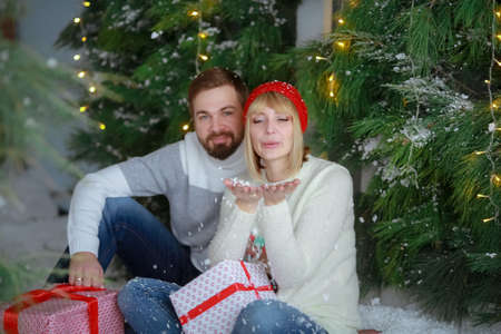 A man with a woman in a photo Studio on the background of an artificial Christmas tree and snow...