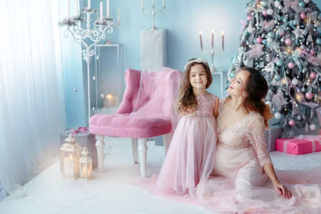 Young expectant pregnant mother for the second time with the first child standing in the room near the Christmas treeの写真素材