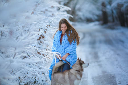 A dog walks in a snowy forest with a woman