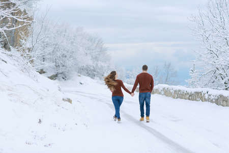 a couple a man and a woman walk together on a snowy roadの写真素材