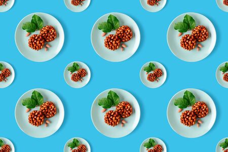 Seamless pattern of healthy natural sweetness of kozinaki are prepared from peanuts, honey and molasses, characterized by the presence of antioxidants and fatty acids in its composition, nuts and green leaves on a plate on a blue background. Horizontal orientation. Georgian and Armenian national dishの写真素材
