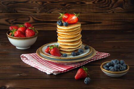 Close-up homemade classic american pancakes with fresh strawberries, blueberries and jars of berries...