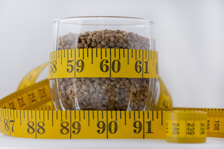 raw buckwheat in a glass, lying next to a measuring tapeの写真素材