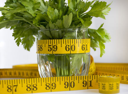 the measuring tape is next to the parsley and greens in a glassの写真素材