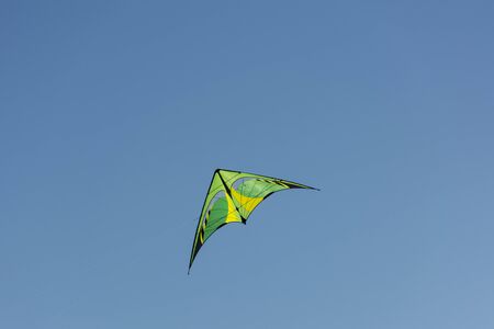 kite yellow and green colors flying in the blue sky, Sunny dayの写真素材