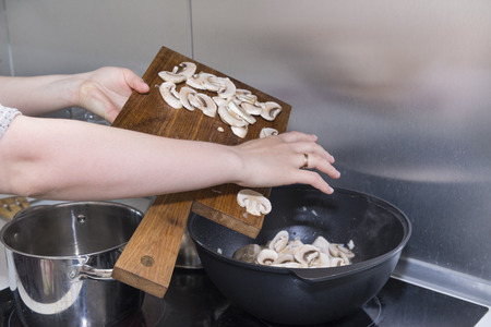girl prepares the mushrooms, pour the mushrooms from the Board into the pan, cooking,の写真素材