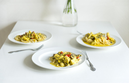 3 plates of pasta with chicken fillet, pepper and mushrooms in cream sauce on the dining table