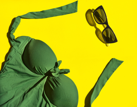 green one-piece swimsuit, sunglasses on yellow background, top view, bikini, flatlayの写真素材