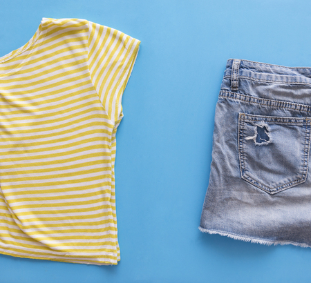 denim blue shorts, striped yellow top, women's summer clothes on blue background top view, flat layの写真素材