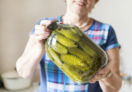 women's hands holding a jar of salted, pickled cucumbers, pickles, foodの写真素材