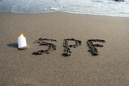 inscription on the sand, the beach, a bottle of sunscreen, sun protection, surf, sea waterの写真素材