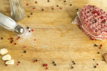 2 raw beef steaks with spices on wooden kitchen Board,  pepper shaker, salt shaker, garlic spices on the tableの写真素材
