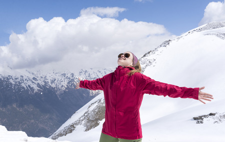 girl in red jacket with arms outstretched in the mountains, Caucasus mountains in winter, mountain...