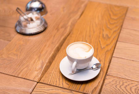 Cup of coffee on a wooden table, sugar bowl, cappuccino in a white Cupの写真素材