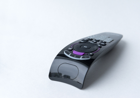 black TV remote with buttons on white backgroundの写真素材