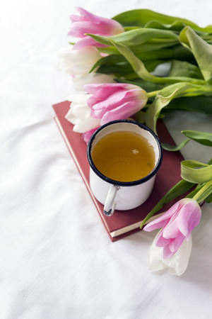 white and pink tulips, tea mug, book, white sheet, flowers, bouquetの写真素材