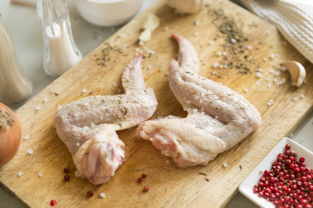 2 raw chicken wings on cutting Board, spices, salt, raw meat,の写真素材