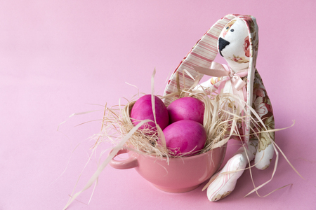 3 pink Easter eggs in a plate, toy rabbit on  pink backgroundの写真素材