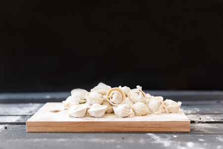 lot of raw dumplings with flour on a dark backgroundの写真素材