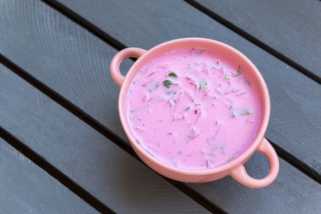 cold beet soup in a pink bowl, pink soup, beetroot soup; gray wooden background,の写真素材