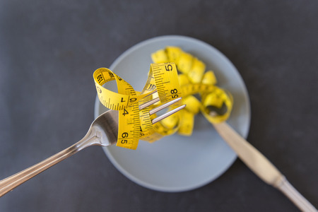 yellow measuring tape on fork and grey plate, knife, dietの写真素材