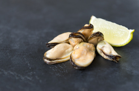 several marinated mussels with a slice of lime on a black background, seafood, shellfish,