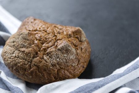 loaf of rye bread with a towel on a dark background, fresh  round bread