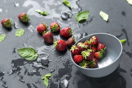plate of berries, strawberries with mint on a black background, water dropsの写真素材