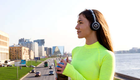 girl in green top with long hair on the bridge over the road on the background of the city with a bottleの写真素材
