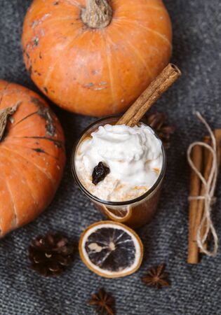1 Cup pumpkin seeds juice with whipped cream and cinnamon, fresh whole pumpkin , slice susanoh of apelsina on a dark knitted cloth, top viewの写真素材