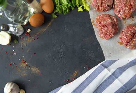 copy space, meat burgers, pork round cutlets with spices on a black background, towel, eggs, garlicの写真素材
